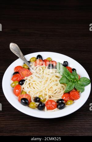 Spaghetti with olives, cherry tomatoes, sprinkled   Parmesan and basil Stock Photo