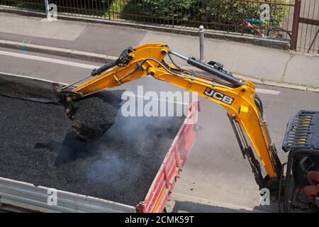 excavator picking up fresh asphalt from dumper truck Stock Photo