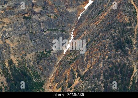 An up close image of the side of a rocky mountain with a crevasse filled with snow and ice cascading downward in Jasper National Park, Alberta Canada, Stock Photo
