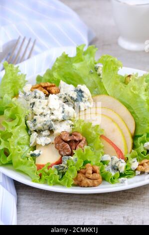 A light lettuce salad with pear slices, gorgonzola pieces and walnut seasoned with olive oil Stock Photo
