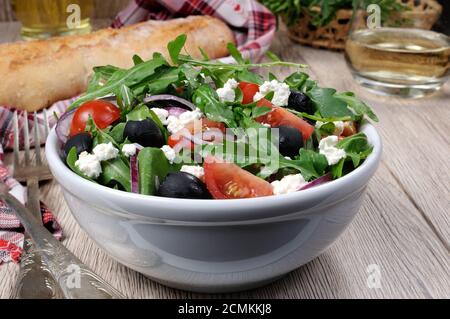 Variation of Greek salad with arugula, cherry slices, feta and olives Stock Photo