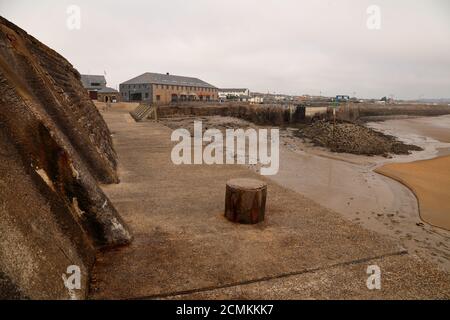 The view from the end of the quay looking across towards the marina and town of Porthcawl with people sitting out eating and drinking at the Harbour. Stock Photo