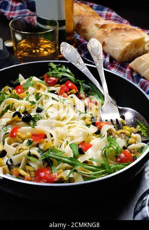 Pasta with crushed olives and cherry tomatoes, arugula. Vertical shot. Stock Photo