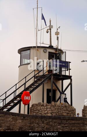 A small round observation tower mounted high up on the sea wall on the inland end of the huge quay that Porthcawl is famous for . Stock Photo