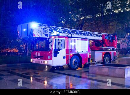 Fire engines in the courtyard of the apartment building where the fire occurred, at night during the rain. Stock Photo