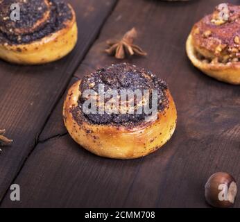 round poppy and nut buns on a brown wooden table Stock Photo