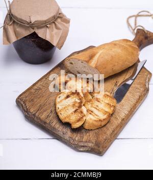 pieces of white bread on a brown wooden board and raspberry jam Stock Photo