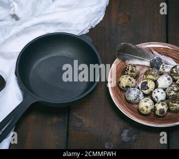 empty round cast-iron frying pan and raw quail eggs in a plate Stock Photo