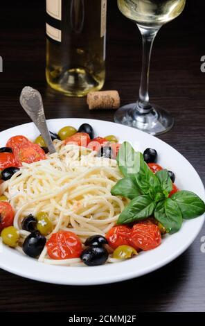 Spaghetti with olives, cherry tomatoes, sprinkled   Parmesan and basil Stock Photo