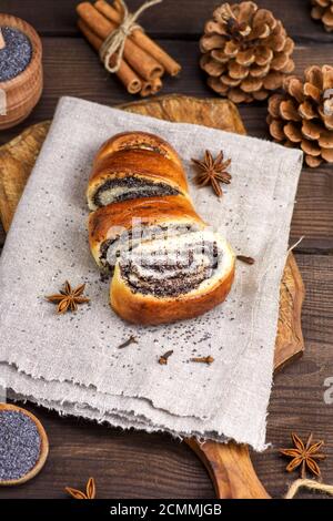 homemade roll with poppy seeds on a brown wooden board Stock Photo