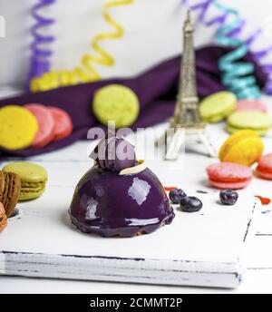 lilac round cake with macaroons on a white wooden board Stock Photo