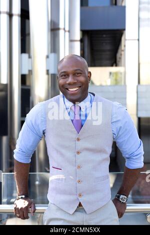 Portrait of a businessman in a suit next to an office building. He is smiling and in a friendly attitude. Stock Photo