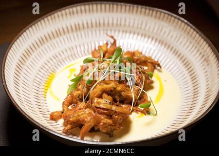 Onion bhaji made with spring onion. The bhaji is served with a smoked cheese sauce. Stock Photo