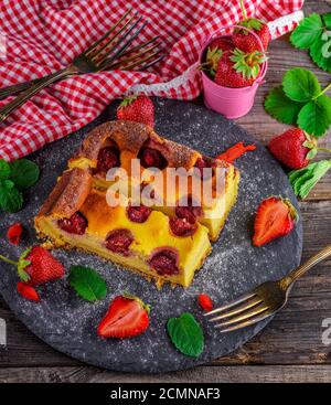 Cheesecake with strawberries on a black graphite plate Stock Photo
