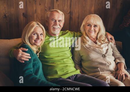 Family meeting thanks giving occasion three elderly people sit sofa hugging wait start dinner living room indoors Stock Photo