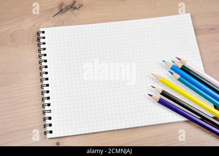 Empty notebook with colorful pencils on a wooden table Stock Photo