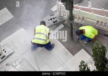 Construction worker with angle grinder repairing a sidewalk. Maintenance concept Stock Photo