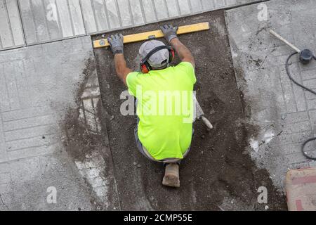 Construction worker with construction level working on a sidewalk. Maintenance concept Stock Photo