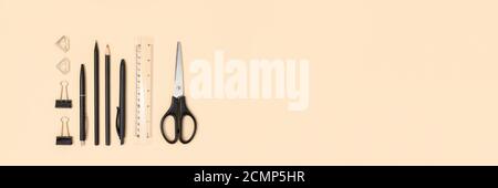 Banner with layout of black office supplies on a beige background. Stationery flat lay. Stock Photo
