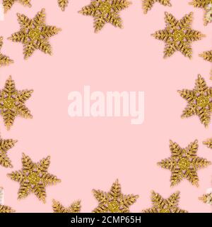 Frame made of golden snowflakes on a pink background. Christmas composition with copy space. Stock Photo