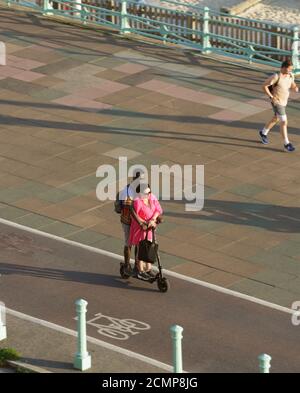 Couple riding on an electric scooter in a cycle lane. Unsharpened Stock Photo