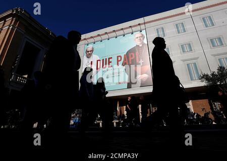People walk past a publicity board advertising the Netflix film ''The Two Popes'', on Via della Conciliazione, a road leading up to St. Peter's square at the Vatican, in Rome, Italy, January 13, 2020. REUTERS/Guglielmo Mangiapane