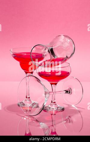 The composition of glasses of various shapes with a red liquid on a light pink background. Stock Photo