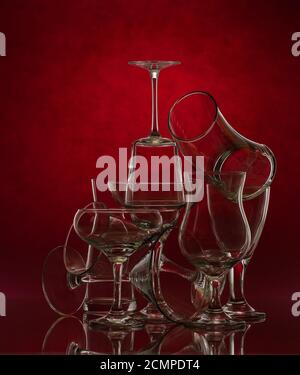 Composition of glass glasses of different shapes on a red background. Art photography. Stock Photo