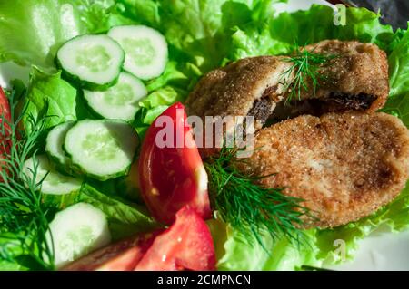 portion of potato cutlets on a plate with vegetables (cucumber, tomato) and greens (lettuce, dill) Stock Photo