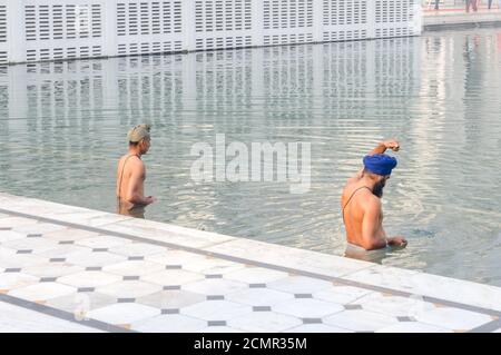 Amritsar, India - November 21, 2011: Sikh pilgrims bathe in the Amrit Sarovar Lake complex of the Golden Temple. The Golden Temple is the main shrine Stock Photo