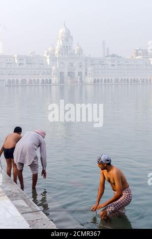 Amritsar, India - November 21, 2011: Sikh pilgrims bathe in the Amrit Sarovar Lake complex of the Golden Temple. The Golden Temple is the main shrine Stock Photo