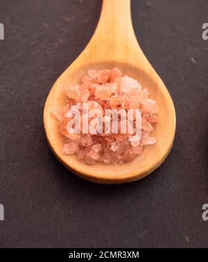 Wooden spoon with Himalayan pink salt on a slate plate Stock Photo