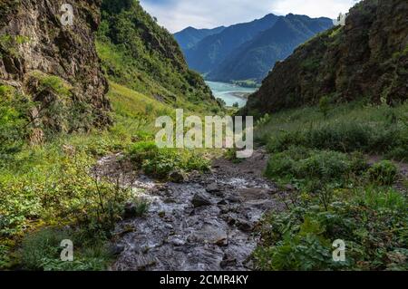 A small stream flows between the mountains Stock Photo