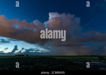 Storm cloud with heavy precipitation after sunset. Some clouds are blurred because of their motion during the long exposure time. Stock Photo