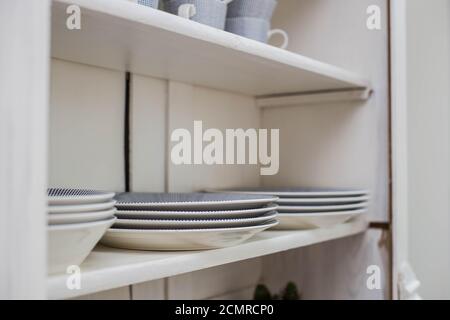 Tableware on a wooden shelf, plates and cups in a closet