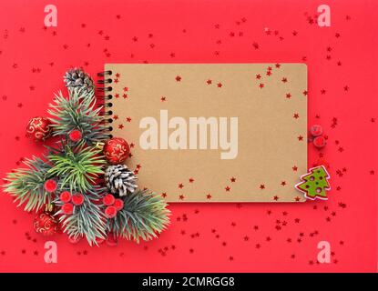 Christmas composition. The notebook and spruce branches on red background. Flat lay, top view, copy space Stock Photo