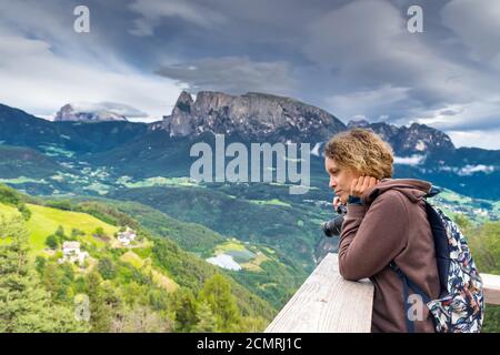 Girl photographer admires the scenery against the backdrop of the mountains. Summer landscape in Italian Dolomites. South Tyrol. Italy. Europe Stock Photo