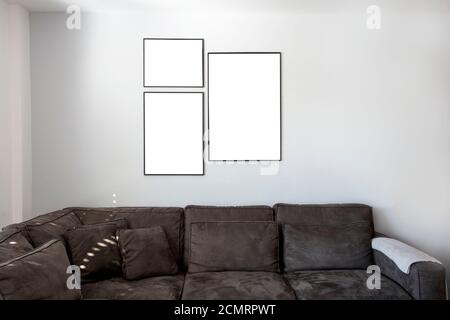 Modern interior dark sofa and tree empty picture frames on the wall, blank poster, canvas space for text in the living room Stock Photo