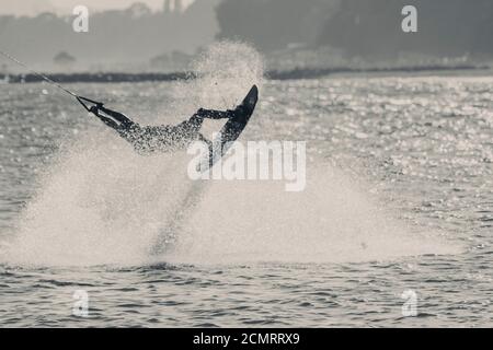 WAKEBOARDING AT THE SEA JUMPING HIGH DOING A BACKFLIP IN BLACK AND WHITE Stock Photo