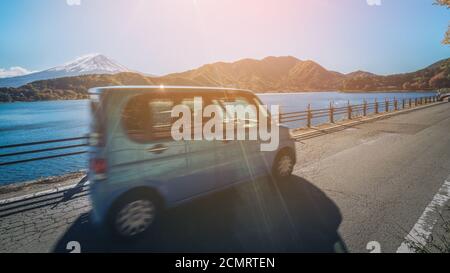Eco car driving near Mt Fuji in Japan with motion blur showing rapid movement on a highway road at Lake Kawaguchiko. Concept of road trip travel Stock Photo