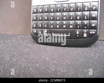 Telephone, Cell phone, vintage black and silver with Qwerty keyboard, FM radio and TV on black background Stock Photo