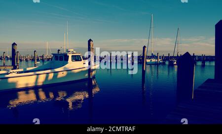 Early morning light on small harbor in Cambridge Maryland, with reflections of the peers and boats in the water. Stock Photo