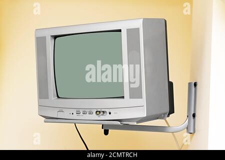 old small TV mounted on wall bracket Stock Photo