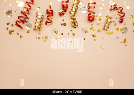 Gold and red Christmas ribbons and confetti on a pink background. Christmas or New Year conceptual background. There is empty space for text at the bottom. Stock Photo