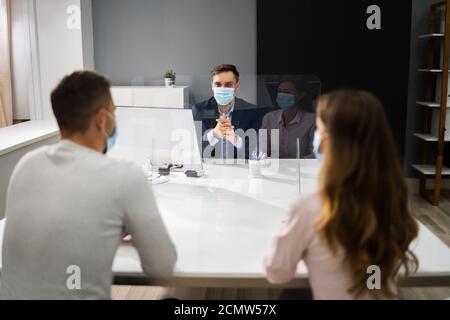 Young Family Couple Meeting Consultant Or Lawyer With Face Masks Stock Photo
