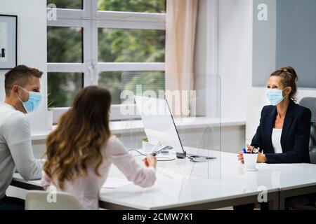 Young Family Couple Meeting Consultant Or Lawyer With Face Masks Stock Photo