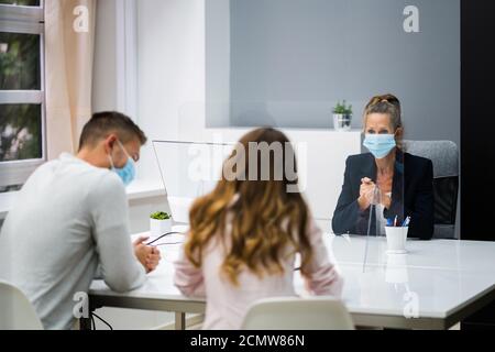 Young Family Couple Meeting Consultant Or Lawyer With Face Masks Stock Photo