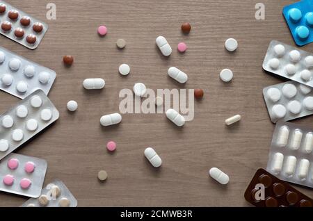 Various tablets on a brown wooden table surface as a background close-up, flat lay. Concept of health care. Stock Photo
