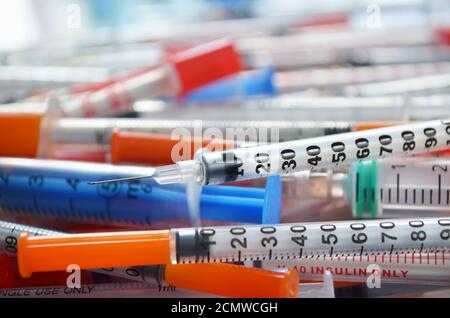 Insulin syringe with an open needle in close-up against the background of other disposable syringes. Shallow depth of field. Healthcare concept Stock Photo