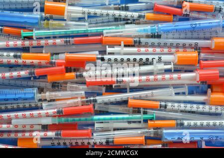 Many different close-up disposable insulin syringes arranged horizontally as a background, top view. Healthcare concept. Stock Photo